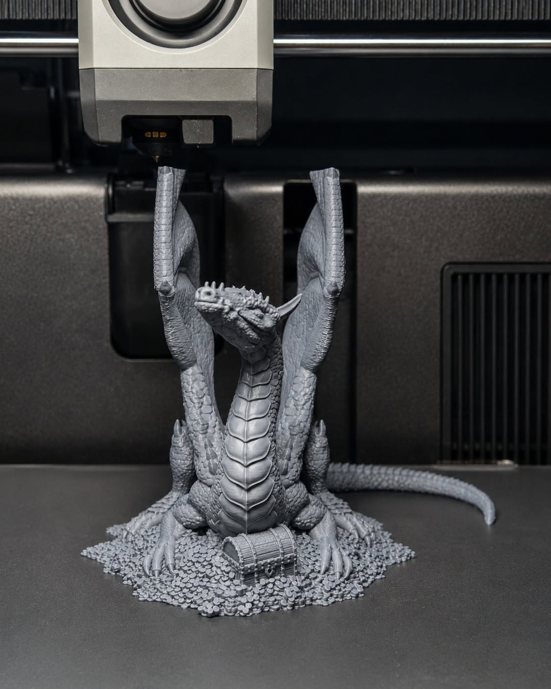 3D-printet drage rett fra printeren, grå PLA, fortsatt festet til printeplaten